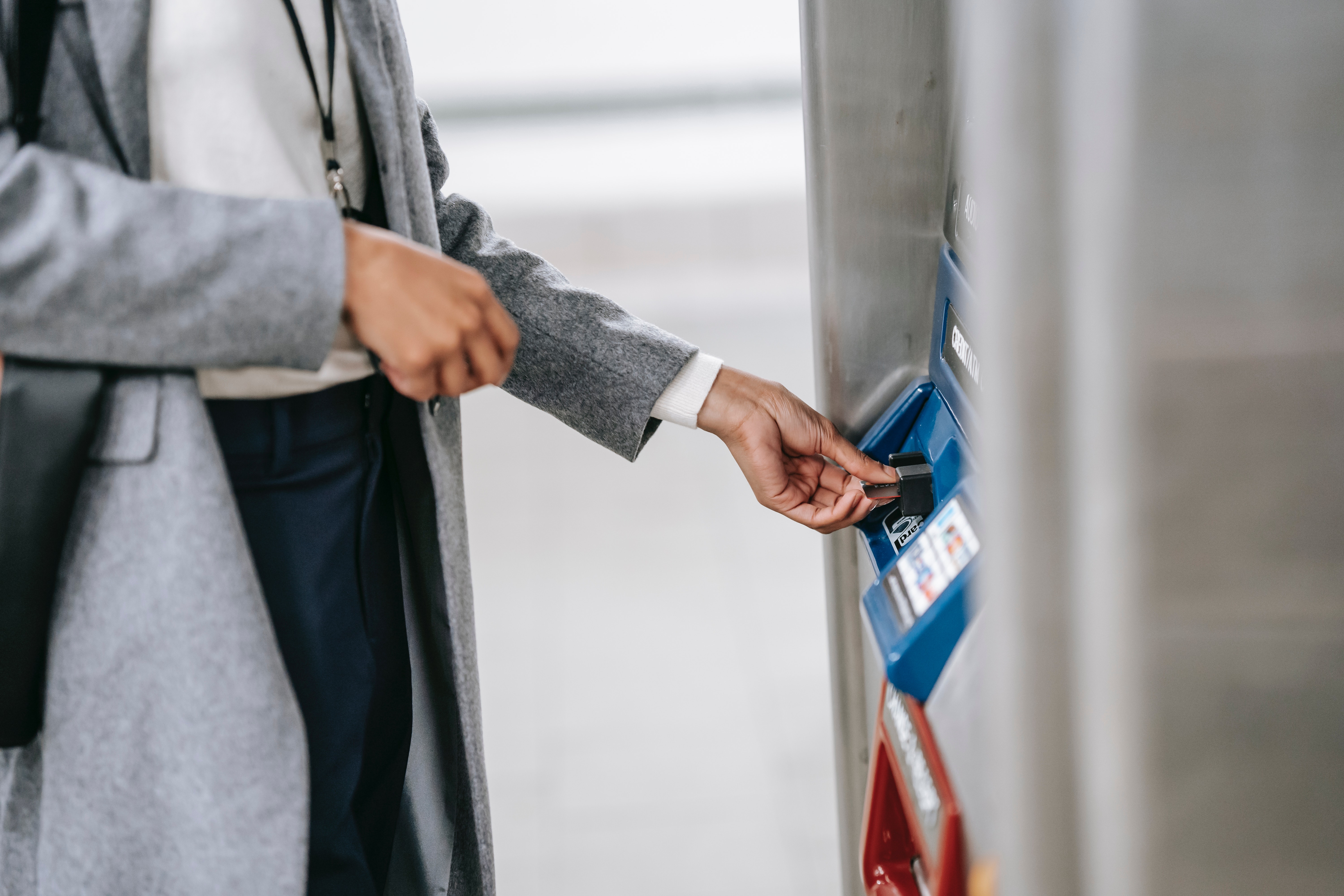 Woman in gray coat withdrawing money from ATM via international-friendly payment
