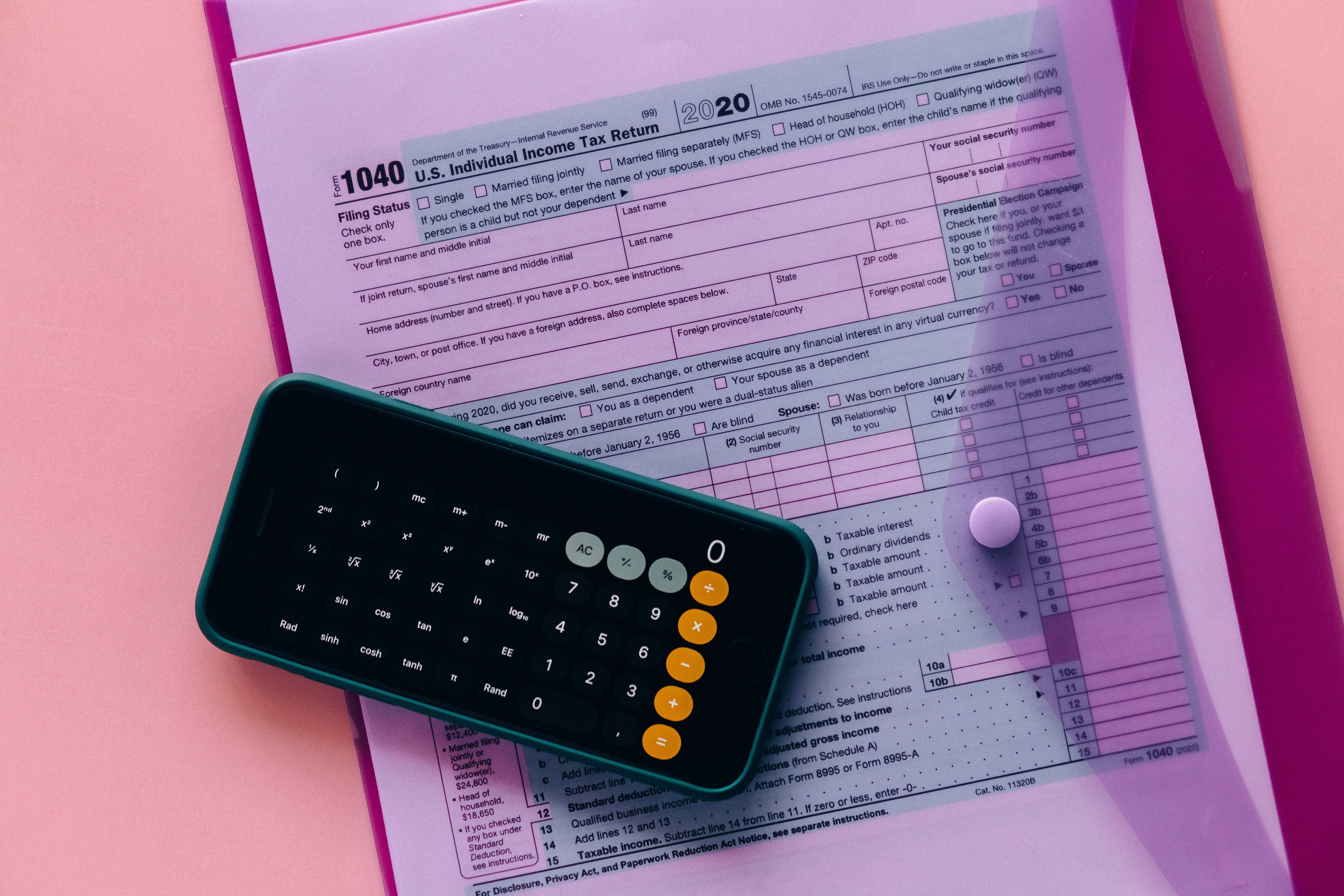 Figuring out remote work taxes with a phone calculator on top of an envelope containing the IRS Form 1040